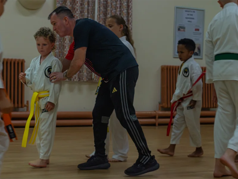 Instructor supporting a junior karate student during training