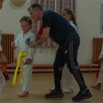 Junior karate student receiving support during training